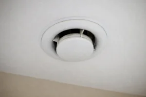 Bouche d'extraction de VMC au plafond d'une pièce, légèrement encrassée