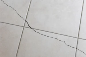 Carrelage interieur clair presentant une fissure traversant plusieurs carreaux apres la pose