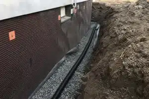 Tranchee de drainage peripherique avec drain perfore et gravier le long des fondations d'une maison
