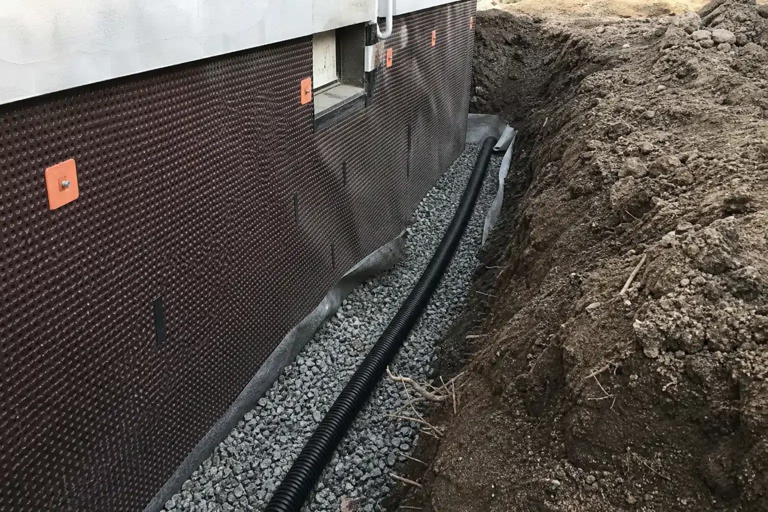 Tranchee de drainage peripherique avec drain perfore et gravier le long des fondations d'une maison