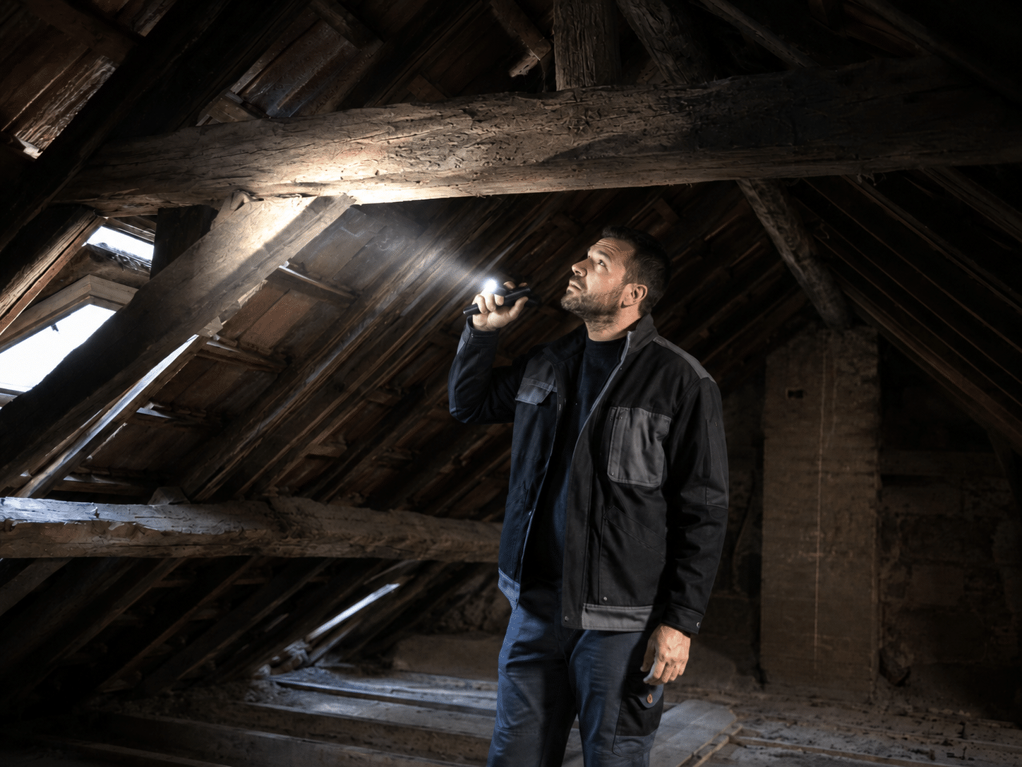 Expert inspectant la charpente d'une maison lors d'une expertise avant achat