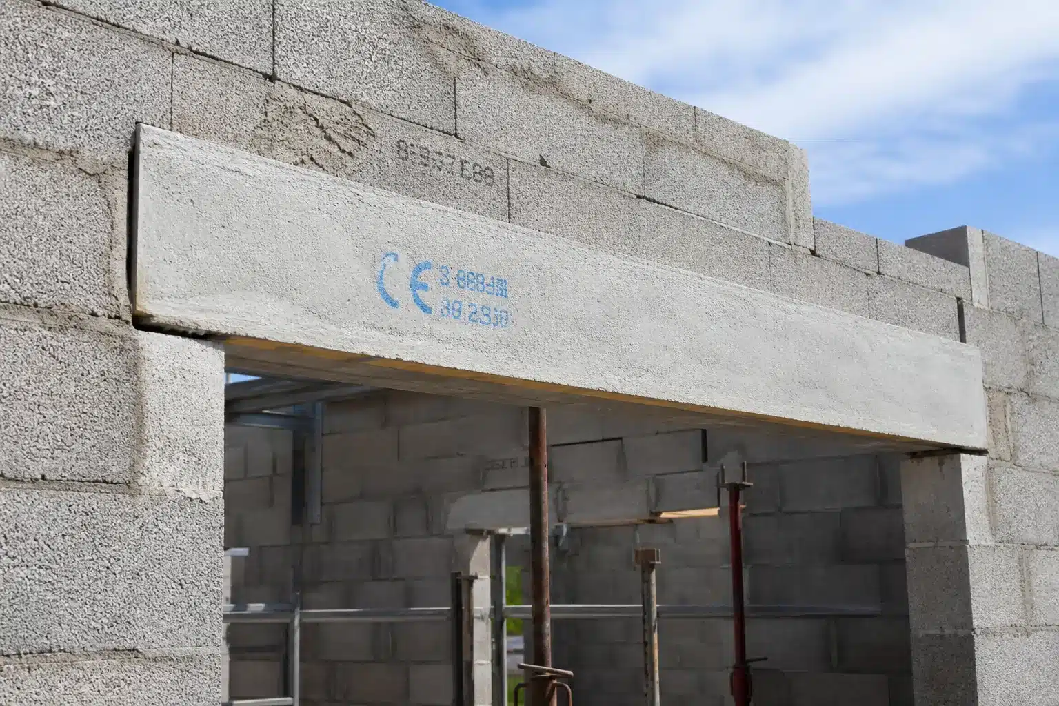 Linteau en béton armé posé au-dessus d'une ouverture de fenêtre sur un mur en parpaings