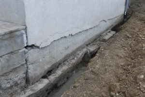 Fondation et bas de mur d'une maison fissurée avec tranchée de reprise en sous oeuvre