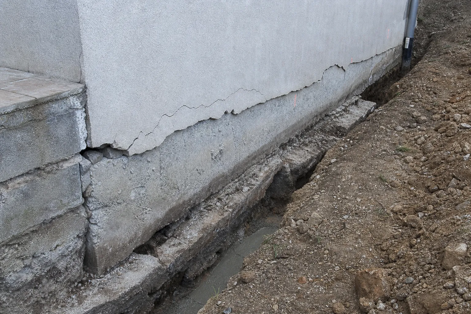 Fondation et bas de mur d'une maison fissurée avec tranchée de reprise en sous oeuvre