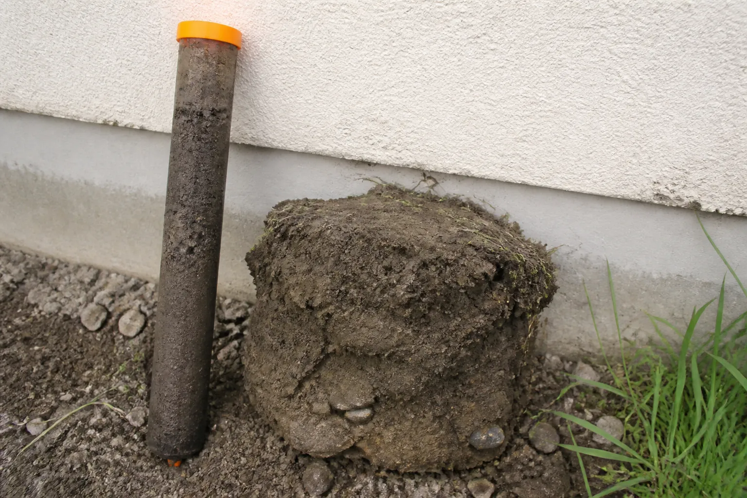 Échantillon de sol argileux prélevé près d'une maison pour une étude géotechnique liée aux fissures