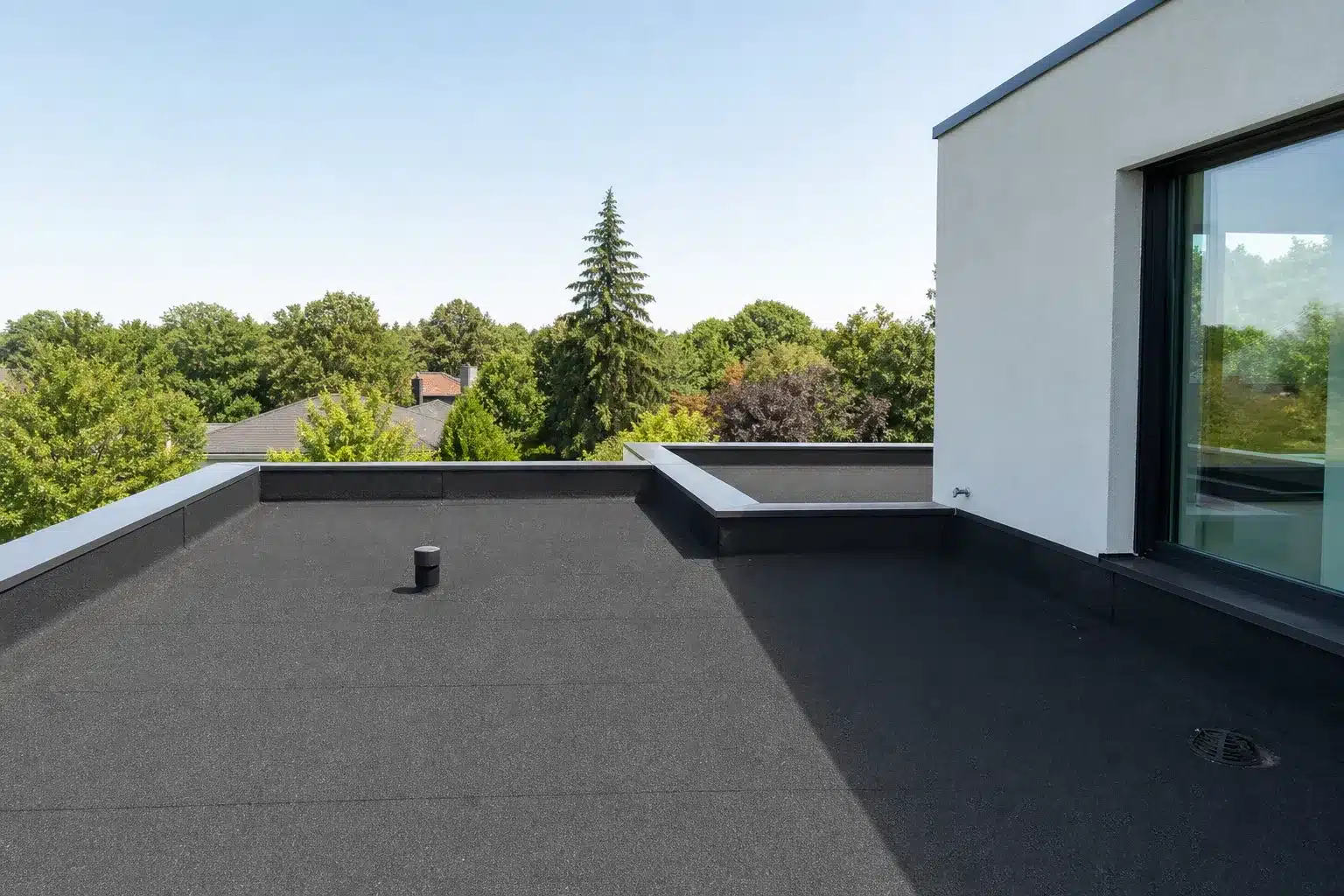 Toiture-terrasse plate avec membrane d'étanchéité bitumineuse et relevés périphériques