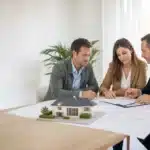 Futurs maîtres d'ouvrage et expert en bâtiment vérifiant le contrat et les garanties d'un constructeur de maison individuelle, illustration de la FAQ CCMI de Check my House