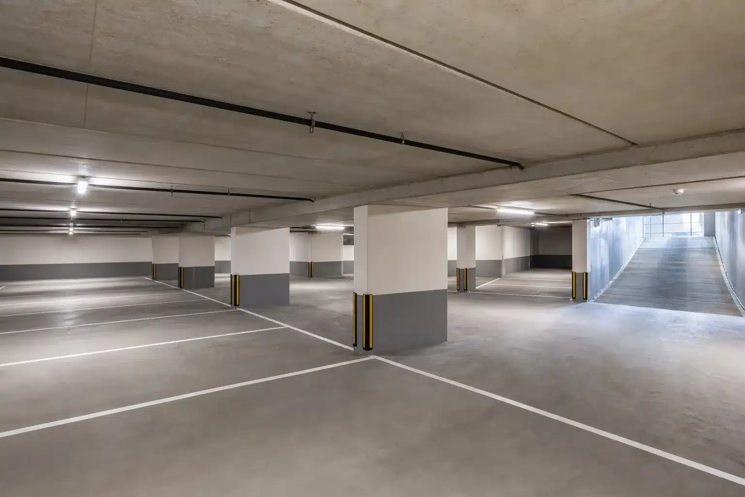 Parking souterrain neuf avec places marquées et rampe d'accès, partie commune d'une copropriété en VEFA