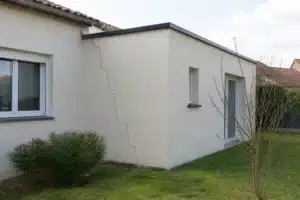 Fissure en escalier sur le mur d'une extension de maison récemment construite par un artisan, au raccord avec la maison existante