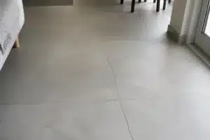 Fissure filante traversant plusieurs carreaux et joints d'un sol carrelé rénové