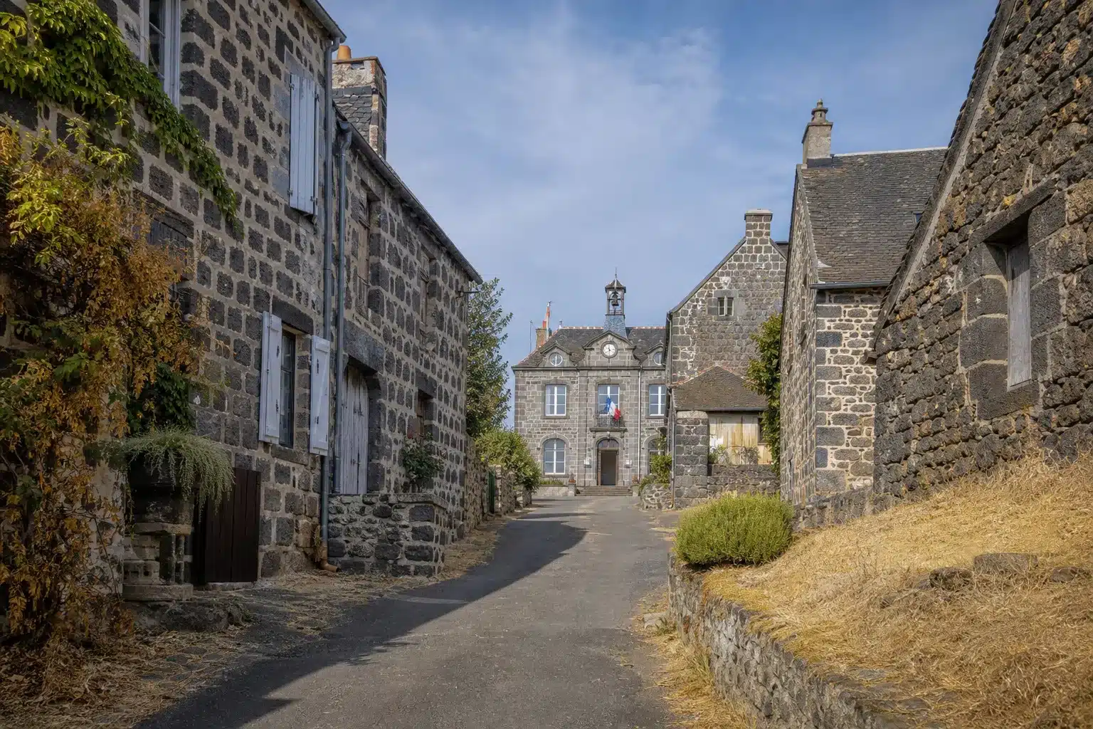 Rue de village dans le Puy-de-Dôme après une sécheresse, mairie au fond