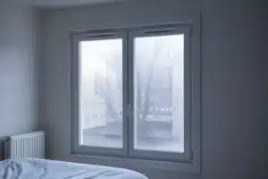 Buée sur la face intérieure d'une fenêtre double vitrage dans la chambre d'un logement neuf en hiver