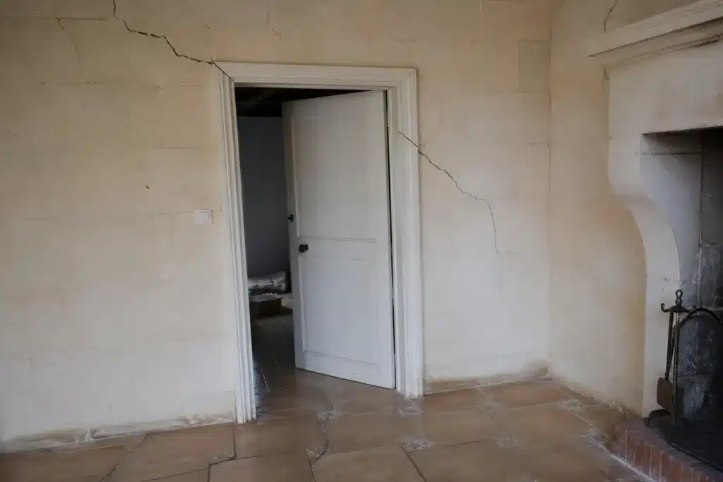 Fissure partant de l'angle d'une porte intérieure, indice de mouvement du sol