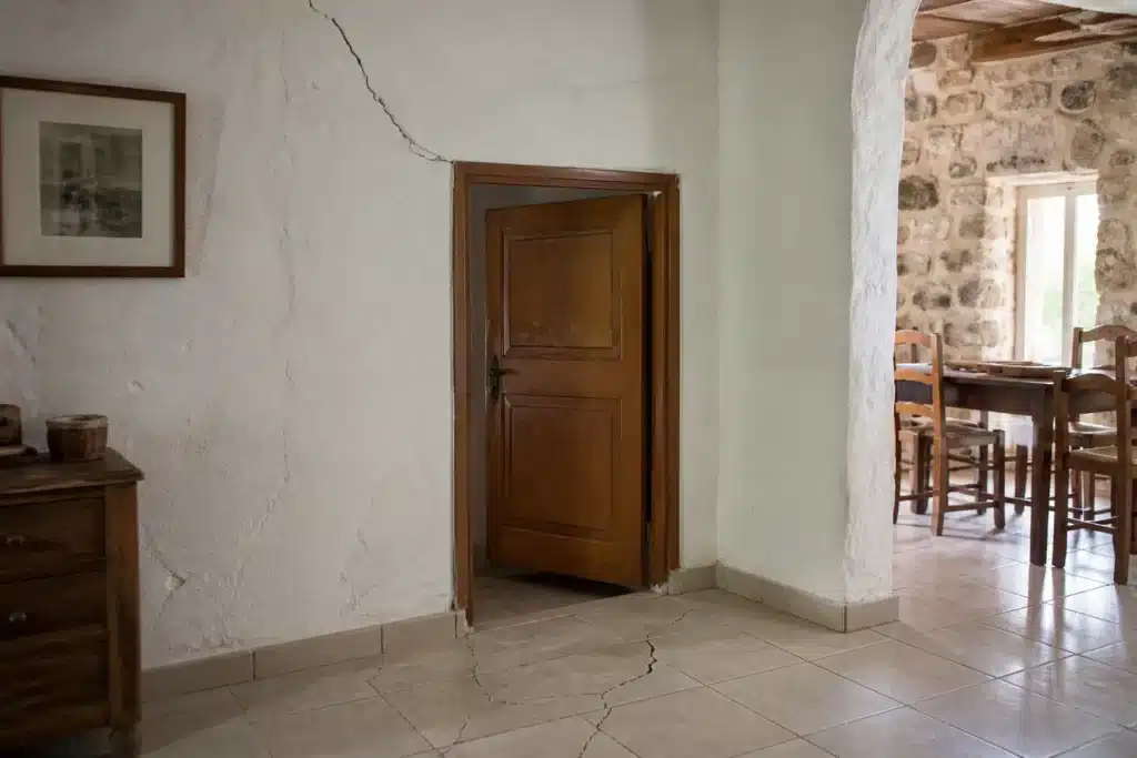 Fissure partant de l'angle d'une porte intérieure, indice de mouvement du sol