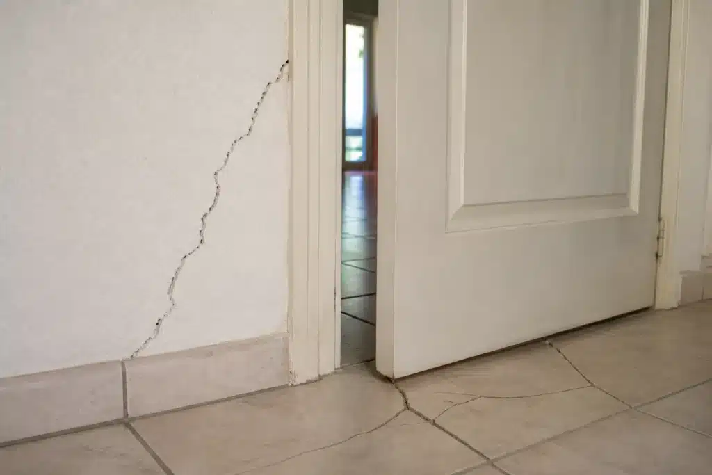 Fissure partant de l'angle d'une porte intérieure, indice de mouvement du sol