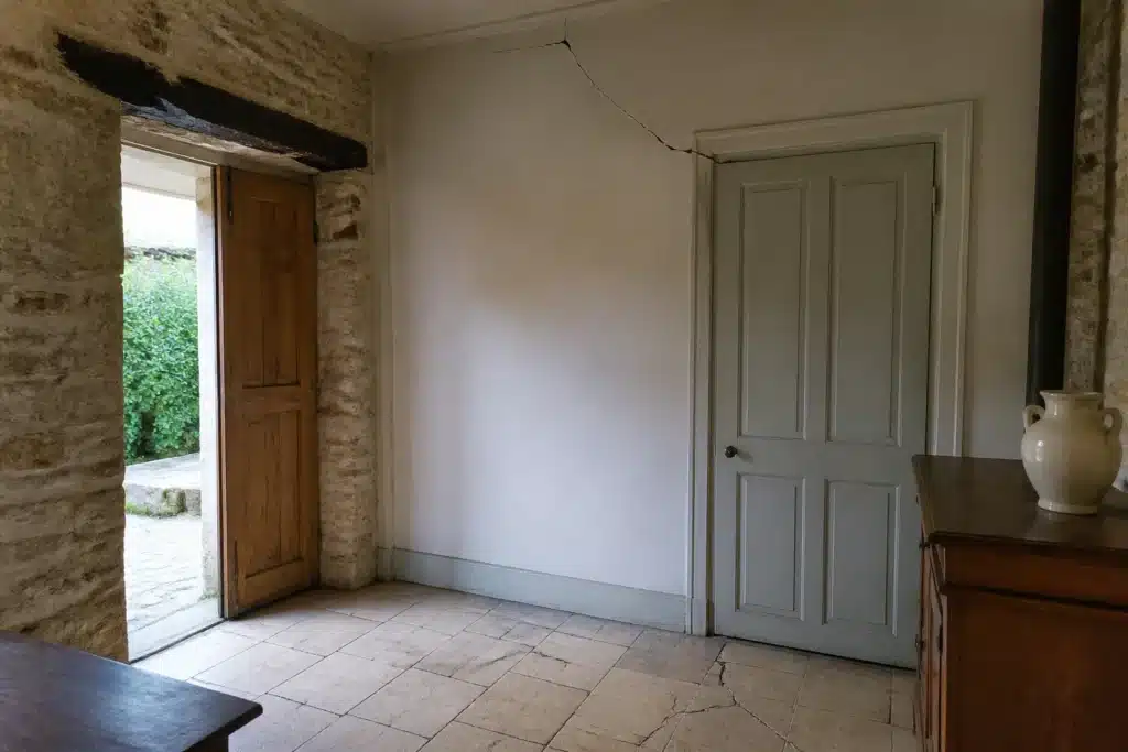 Fissure partant de l'angle d'une porte intérieure, indice de mouvement du sol