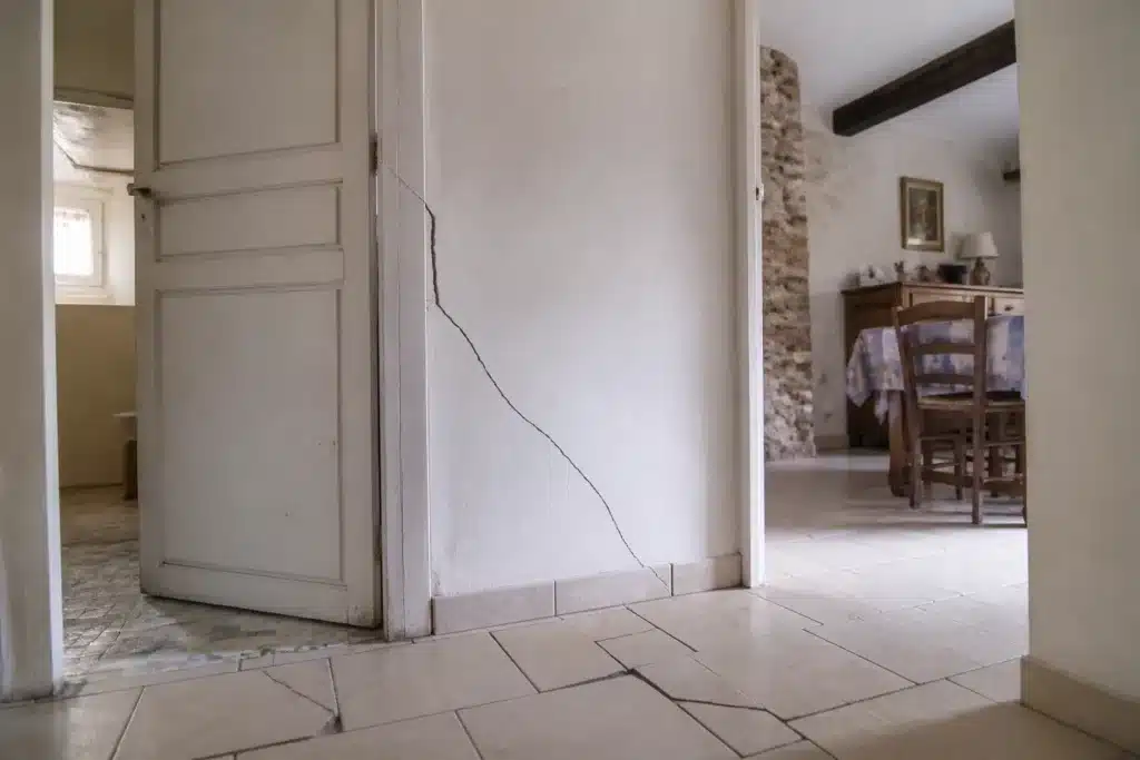 Fissure partant de l'angle d'une porte intérieure, indice de mouvement du sol