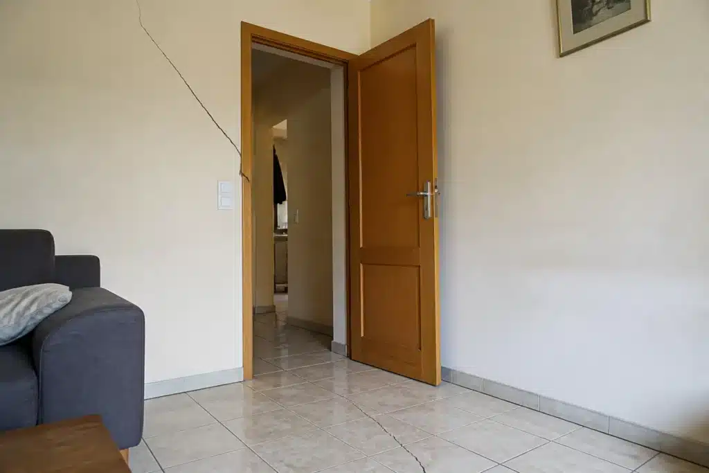 Fissure partant de l'angle d'une porte intérieure, indice de mouvement du sol