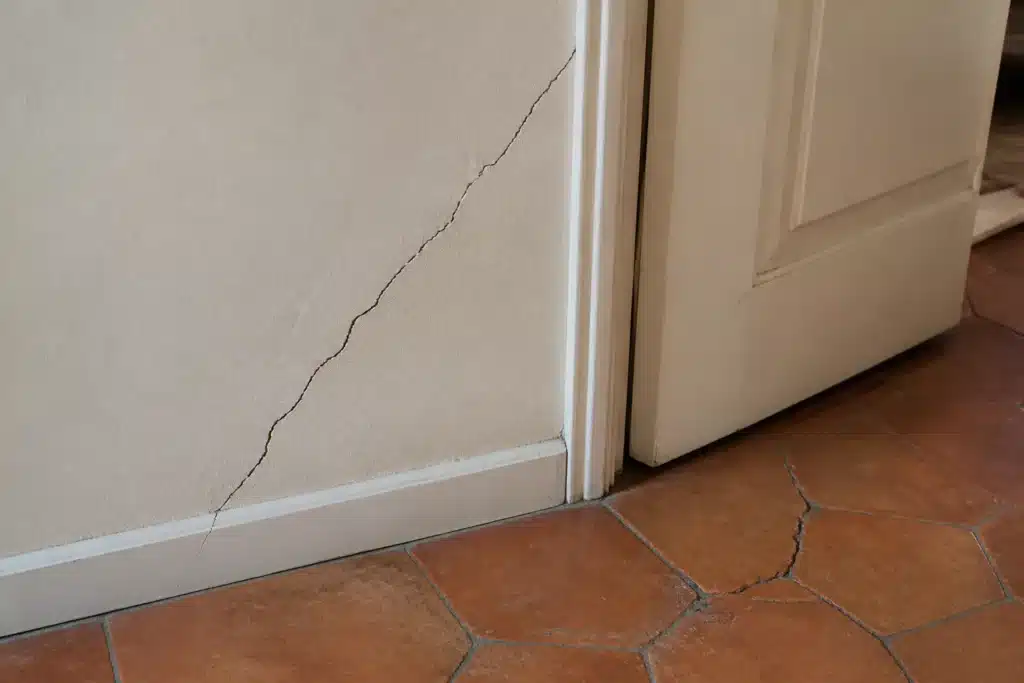 Fissure partant de l'angle d'une porte intérieure, indice de mouvement du sol