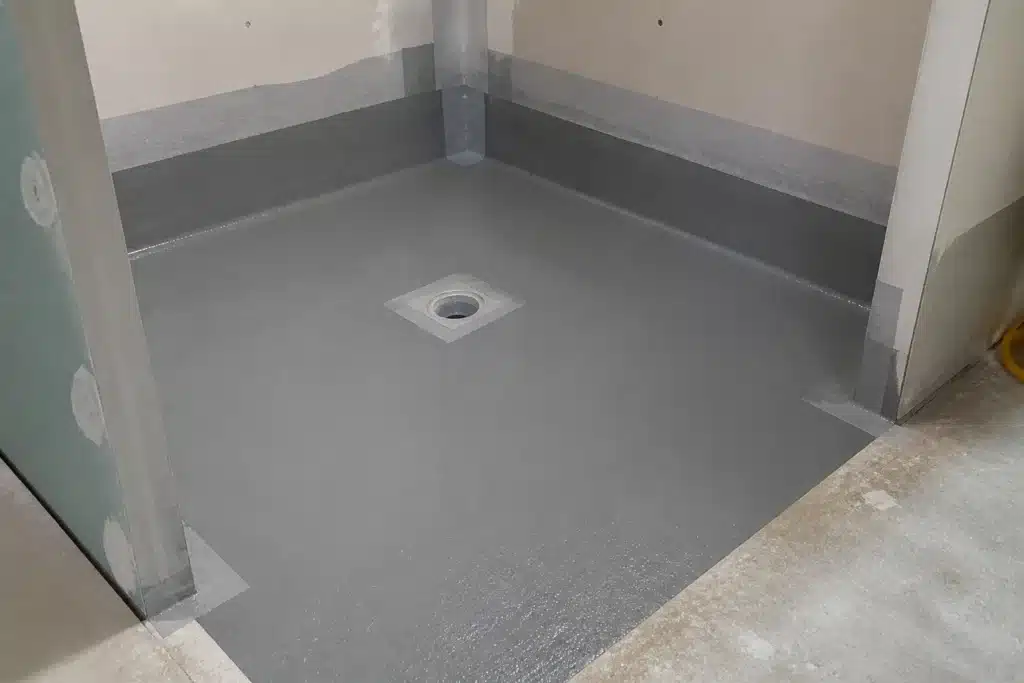 Système d'étanchéité liquide appliqué au sol d'une douche à l'italienne avec relevés en pied de mur et siphon à platine avant carrelage