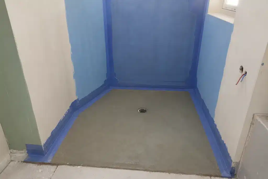 Étanchéité sous carrelage appliquée au sol et en remontée murale d'une douche à l'italienne avant la pose du carrelage