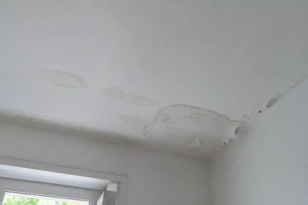 Infiltration d'eau et auréoles au plafond d'une pièce sous une toiture-terrasse rénovée, constatées quelques mois après les travaux