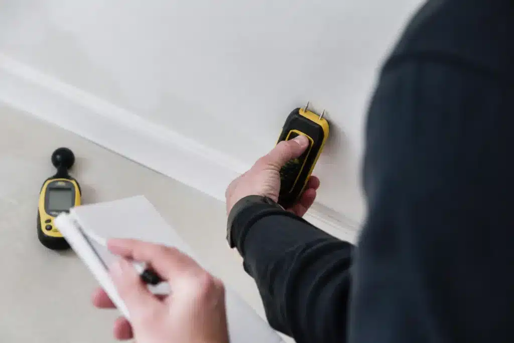 Mesure de l'humidité au bas d'un mur à l'humidimètre par un expert dans un logement neuf