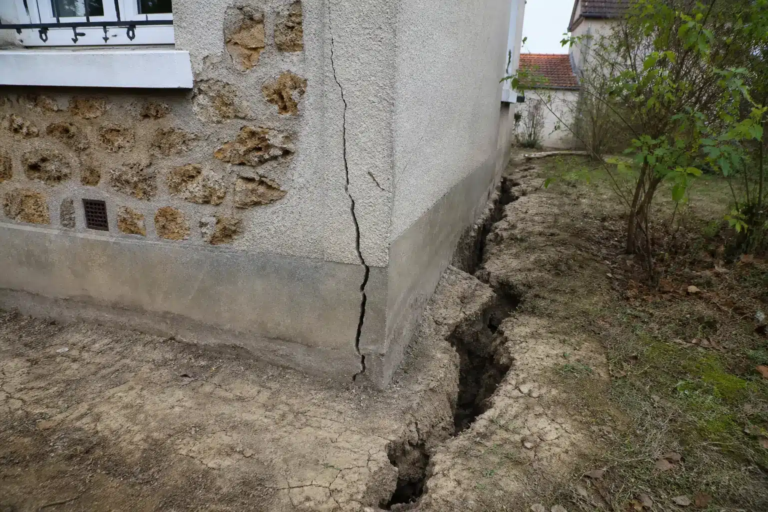 Sol argileux fendu au pied d'une maison dans les Yvelines, retrait-gonflement des argiles